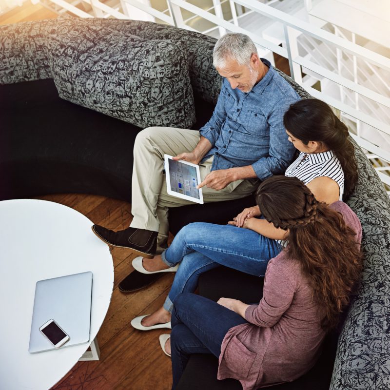 High angle shot of three colleagues looking at a digital tablet.
